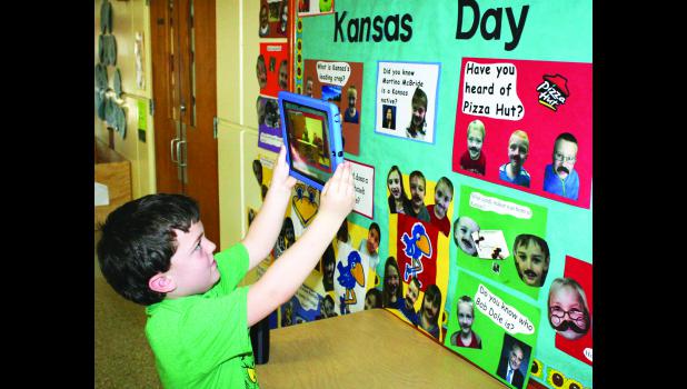 by Brian Sanders Sterrett McCauley, a first-grade student at Colorado Elementary School in Holton, used an iPad with an “augmented reality” (AR) app to answer a question about whether country singer Martina McBride is a Kansas native (answer: McBride was born and raised in Barber County). The school is displaying a bulletin board this week that uses AR technology to answer ques¬tions about Kansas people, places and things in honor of Kansas Day, which is Thursday.