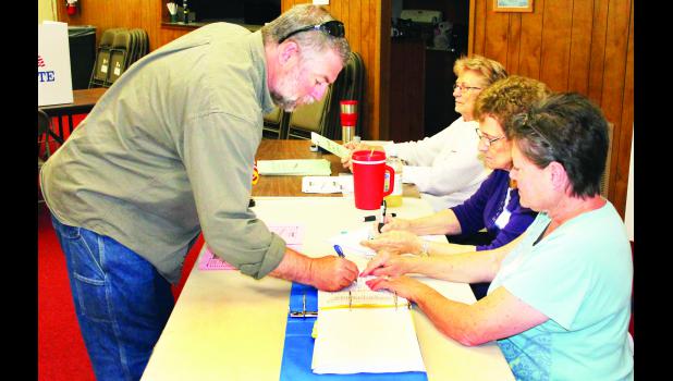 by Brian Sanders Mark McKinsey of Holton (left) signed in to vote during Tuesday’s general election with some help from election volunteers Gayle Dunn (right), Cletamae Brown (second from right) and Carol Baum at the Veterans Club. Tuesday’s election was the first to be held at the Vets Club, as opposed to the former Jackson County Fair Building, a polling place for Holton voters in previous elections. Signs were placed outside the old fair building to remind people of the new polling place.