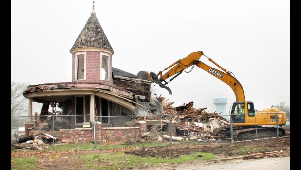Travis Amon (at right) of Holton’s Brahma Excavating used an excavator on Wednesday afternoon to demolish the old Chandler house across the street from Colorado Elementary School. The historic house was the last one standing on the block to the west of the school, which has been cleared for construction of the new Holton Elementary School. The new school is expected to be ready in time for the 2016-17 school year, it was reported. (Photo by Brian Sanders)