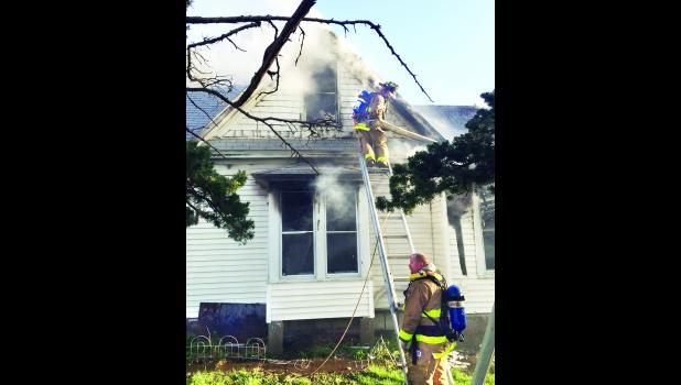 by David Powls Firefighters from fire departments in southern Jackson County are shown battling a fire Tuesday morning at 104 Highland Ave. in Hoyt. It was reported that all the occupants of the house were able to exit the house, including one person who jumped to the ground from an upstairs window.