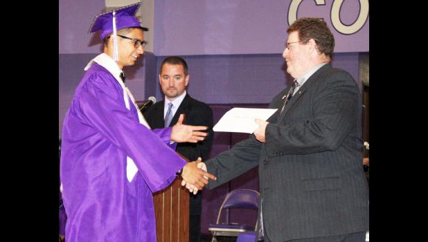 Royal Valley High School graduating senior Eugene Masquat (left) shook hands with USD 337 school board member Jim O’Toole (right) before collecting his high school diploma during Sunday’s RVHS commencement, in which Masquat and 62 other Panther seniors brought their high school years to a close. Also shown in the photo above is RVHS assistant principal Charlie Nimz. (Photo by Brian Sanders)