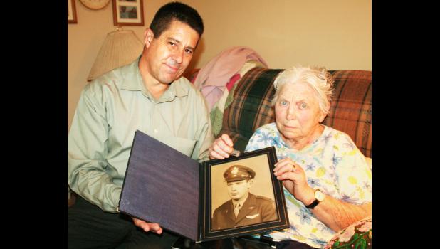 Arizona resident Robert Kropp (left) on Thursday visited the Topeka home of Holton High School alumna Viola (Richter) Row (right) to return a bracelet that Row purchased for her boyfriend, the late George Zellers (in frame), also an HHS graduate. Kropp’s discovery of the bracelet in the Arizona desert touched off a search for facts about Zellers, as well as the woman who purchased the bracelet and had “With love, Viola,” engraved on the back. (Photo by Brian Sanders)