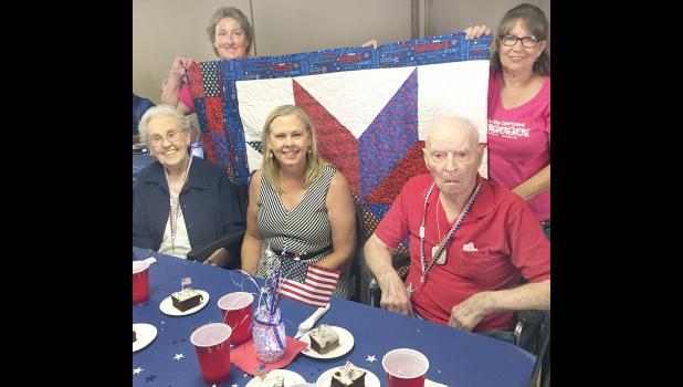 Local military veterans Dorothy Rogers (at left on front row) and Charles Scheidegger (at right on front row) were among 50 veterans honored at the second-annual Quilts of Valor event on Saturday. Organizers Julie Bahret (rear left) and Connie Morgan (rear right) helped organize the dinner and presentation. Also shown is Rogers’ daughter, Jackie Sommers of Topeka. More than 300 dinners were served at the event. (Photo by David Powls)
