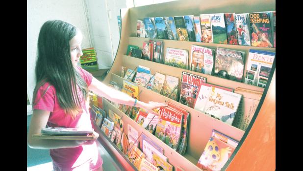 Abby Hopkins, 11, scanned the selection of magazines and books offered at the new volunteer-led library that is located in the Denison Community Building. (Photo by Ali Holcomb)