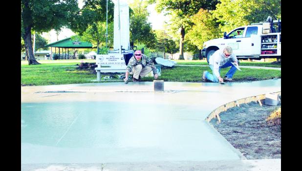Trent Reed (left) and Lane Slocum, working for Sullivan Construction of Holton, smoothed out concrete Friday morning at a construction site in Linscott Park where a new monument honoring Jackson County’s recipients of the Purple Heart Medal will be placed in the near future. Veterans Day has been set as a tentative date for unveiling of the new monument, it was reported. (Photo by Brian Sanders)