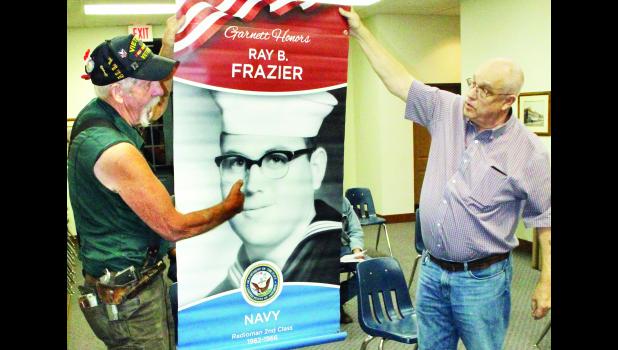 by Brian Sanders Area veterans Les Crawshaw (shown above at left) and Mike Wilson hold up an example of a three-foot by five-foot patriotic banner from the Garnett community Monday evening at the Holton City Commission meeting.