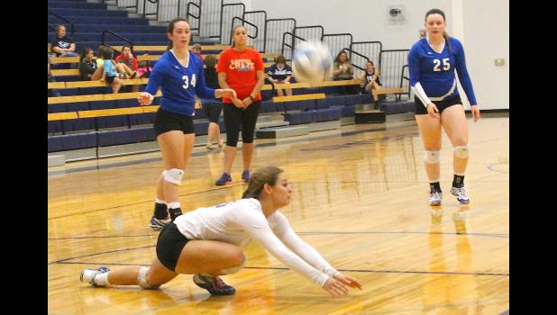 Photo by Kelly Breckunitch Holton's Courtney Boswell (shown above, back left) and Shari Riley (back right) look on as teammate Ashlyn Weilert (front) dives forward to return a serve in a match against Sabetha. That trio has anchored the back row for the Wildcats' strong defense, which helped the team to a sweep of Jeff West in its most recent matches.