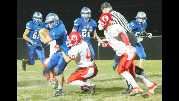 By Kelly Breckunitch Wildcat Justin Rieschick (shown above, left) tries to break free from the grasp of a Trojan defender in regional competition. Rieschick played a hand in the team's efficient offensive night, contributing two touchdowns in the 54-8 victory.