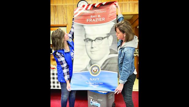 Submitted photo During a recent Holton/Jackson County Chamber of Commerce luncheon, Lindsay Alley (shown above at left) and Laura Golden (at right) helped display a sample of a patriotic banner that is being sold here to honor veterans.