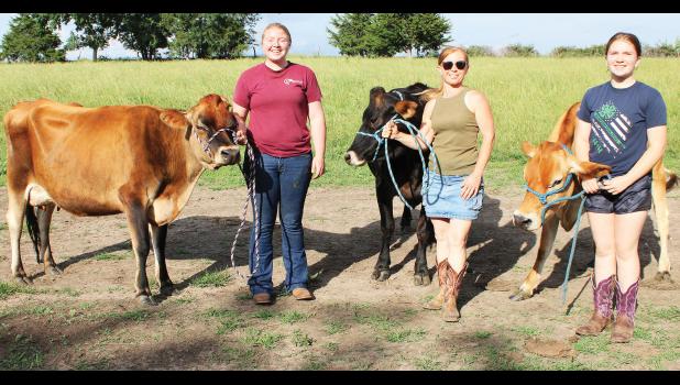 Sharron Holliday (center) of rural Denison and her daughters, Sidney Eisman (at left) and Sophia Holliday (at right) are proud of their small herd of Jersey milk cows. (Photo by Brian Sanders)