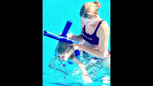 The first round of group swim lessons was held at the Holton swimming pool last week with a second session to be held July 13-17. Here, lifeguard Kamber Wommack (at right) is shown helping Chandler Strube (at left) during a Level 1 lesson. An average of 80 to 90 people have been visiting the pool each day this summer. (Photo by David Powls)
