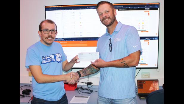 Holton High School e-sports coach Dillon Kathrens (at left) recently received a $5,044.72 donation from Giant Communications general manager Austin Taylor (at right) for the e-sports program at HHS. (Photo by Brian Sanders)