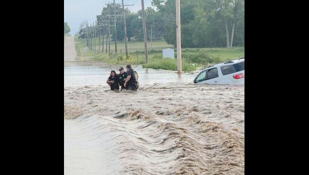 Three people were rescued from floodwaters in Jackson County early Friday morning following heavy rains. In this photo, Holton Police Officers Chad Ballenger (center) and Justin Keller (at right) are shown helping an unnamed flood victim navigate floodwaters after her vehicle was swept off Q.4 Road just north of Holton near Elk Creek. (Photo courtesy of Holton Police Department)