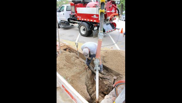 Holton city employee Kendall Fox used the city’s Ring-O-Matic vacuum excavator to remove excess water from a pit on the south side of Holton’s Town Square  last Friday as part of work needed to repair a water leak in a curb spout located in front of Ozzie Bakes. Haug Construction of Holton was also involved in the repair work, Fox said. (Photo by Brian Sanders)