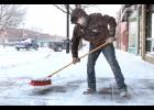 After a snowstorm late last Wednesday and early Thursday dumped about six inches of snow on the Holton area, some youngsters who got the day off from school were put to work removing snow from sidewalks and driveways. Luke Gallagher, a freshman at Holton High School, was no exception, sweeping snow from the sidewalk in front of Lifetime Eye Care on the south side of Holton’s Town Square. (Photo by Brian Sanders)
