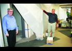 Scott Foster (left), owner of Foster Ford in Holton, stood in the showroom of the Ford dealership he has owned and operated for more than three decades while Leroy Krogmann, service manager at Foster Ford, pulled back a sheet of plastic to reveal some of the renovation work that has been going on at the dealership. The renovation work is being done as part of Ford Motor Company’s Trustmark program. (Photo by Brian Sanders)