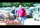 On Tuesday morning, the monthly food distribution provided by Harvesters was held at Countryside Park in Holton. Volunteers (from left) Dave Snyder, Taven Dick and Roger Rethman are shown preparing the food to be handed out to residents. In the background,  a large line of cars had already formed at the park prior to the food even arriving by truck. 		                           