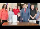 Gov. Laura Kelly (center) ceremonially signed SB 1, providing Kansans with about $2 billion in tax relief over the next 5 years, during a recent visit with Kansas Sen. Dennis Pyle to the Jackson County Courthouse. Shown behind Kelly are, from left, Glenda DuBoise (AARP Kansas), Janette Hammack (Chamber of Commerce), Rick Fleming (AARP Kansas), county commissioners Mark Pruett and Keith Kelly, Pyle, county commissioner Dan Brenner and Edith Gaines (AARP Kansas). (Photo by Brian Sanders)