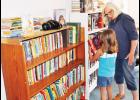 Vickie Wold (right), one of the organizers for the new free public library in Denison, helped Penny Hopkins, 7, select a book to check out during the library’s grand opening on Friday. (Photo by Ali Holcomb)