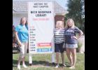 A new sign in front of Beck Bookman Library marks donations received for the library’s expansion and renovation project, with a fund-raising goal of $2.5 million. Shown are, from left, Amy Austin, library director; Sandee Morris, library board president; and Carli Keling, Friends Of Beck Bookman Library member.  (Photo by Ali Holcomb)