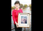 Holton resident Jan Hodge stands in the photo above with a photo of herself and her late husband, Harold, who will be inducted into the Holton/Jackson County Chamber of Commerce Hall of Fame in February. Behind Hodge is the water fountain installed at Elkhorn Lake in Rafters Park earlier this year in Harold’s memory, made possible by a donation from Jan. (Photo by Brian Sanders)