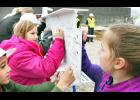Central Elementary School third-grade students (from left to right) Maverick Hug, Abby Wellman and Addyson Schumaker signed their names on a white steel beam to be placed as the final beam on the structure of the new Holton Elementary School during a "topping off" ceremony on Monday afternoon. 